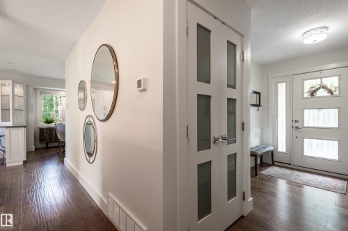 Entryway featuring wood-finish flooring, a contemporary front door with three frosted glass panels, a full-length sidelight, and a modern flush-mount ceiling light - 14604 92A Avenue, Edmonton, AB - Indoor Photo Showing Other Room