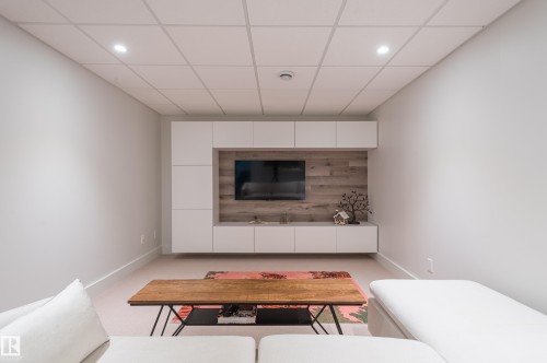 Living area featuring a floating media console with integrated storage, wood-finish accent wall, recessed lighting, and a drop ceiling - 14604 92A Avenue, Edmonton, AB - Indoor Photo Showing Living Room
