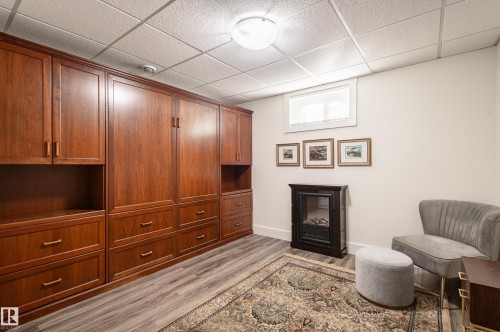 Custom built-in cabinetry with rich wood finish, integrated storage, and display shelving - 14604 92A Avenue, Edmonton, AB - Indoor With Fireplace