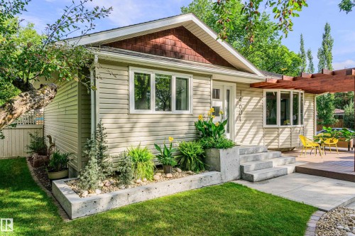 Single-story residence featuring light-colored siding, a prominent front gable with wood-shingle accents, and multiple large windows - 14604 92A Avenue, Edmonton, AB - Outdoor