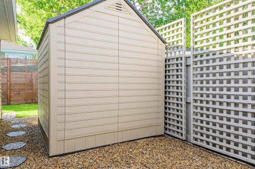 Freestanding beige storage shed with a dark roof and gable vent - 14604 92A Avenue, Edmonton, AB - Outdoor With Exterior