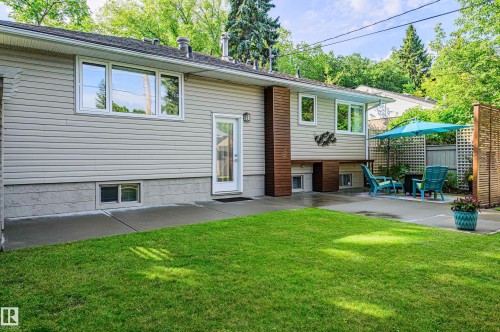 Expansive backyard featuring a manicured lawn, concrete patio, and mature trees surrounding the property - 14604 92A Avenue, Edmonton, AB - Outdoor