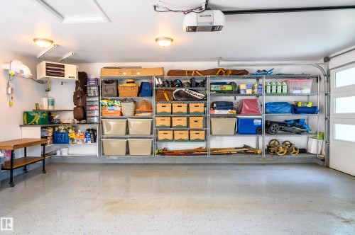 Spacious garage featuring an epoxy-coated concrete floor, overhead lighting, and built-in wall shelving - 14604 92A Avenue, Edmonton, AB - Indoor Photo Showing Garage