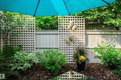 Manicured garden featuring a wood lattice fence, rich dark mulch, and established perimeter plantings - 14604 92A Avenue, Edmonton, AB - Outdoor