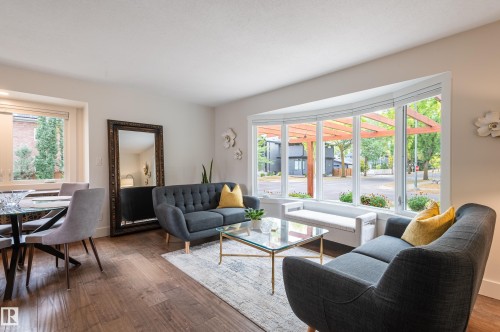 Bay window with integrated bench seating, wood-finish flooring, and a glass-top table - 14604 92A Avenue, Edmonton, AB - Indoor Photo Showing Living Room