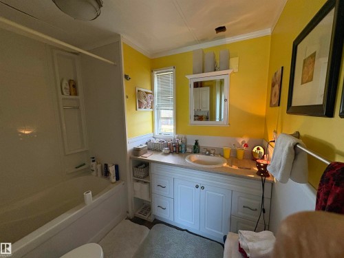 Bathroom featuring a white vanity with panel cabinetry and a light-toned countertop, a white drop-in sink with a chrome faucet, and a white medicine cabinet with an integrated mirror - 115 2Nd Street E, Derwent, AB - Indoor Photo Showing Bathroom