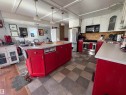 Spacious kitchen featuring a large central island with bright red cabinetry, white upper cabinetry, and a stainless steel appliance suite including a refrigerator, range, and microwave. - 115 2Nd Street E, Derwent, AB  - Indoor Photo Showing Kitchen With Double Sink 