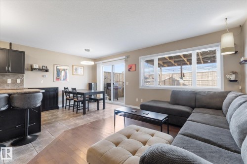Open-concept living space featuring wood-finish flooring, a large picture window, and a sliding glass door providing access to the patio - 21818 99A Avenue, Edmonton, AB - Indoor Photo Showing Living Room