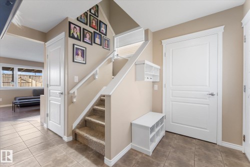 Foyer featuring neutral-toned tile flooring and a carpeted staircase with white railings - 21818 99A Avenue, Edmonton, AB - Indoor Photo Showing Other Room