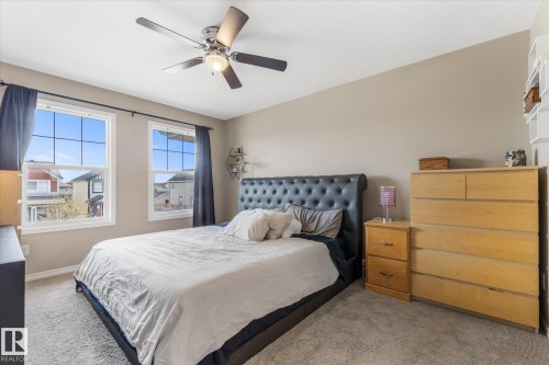 Carpeted bedroom featuring a ceiling fan, two double-hung windows, and neutral wall tones - 21818 99A Avenue, Edmonton, AB - Indoor Photo Showing Bedroom