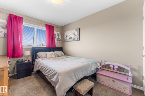 Carpeted bedroom featuring a large window with blinds, neutral wall paint, and a built-in overhead light fixture - 21818 99A Avenue, Edmonton, AB - Indoor Photo Showing Bedroom