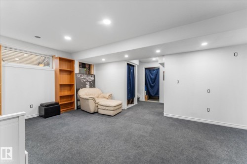 Carpeted lower level with recessed lighting, an egress window, and built-in wood shelving - 21818 99A Avenue, Edmonton, AB - Indoor