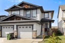 Contemporary two-story exterior with light-colored siding, dark trim accents, and a dual-car garage featuring individual doors with window inserts - 21818 99A Avenue, Edmonton, AB  - Outdoor With Facade 