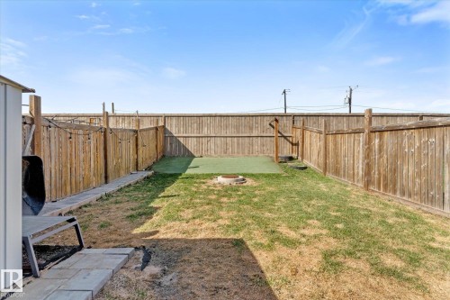 Fenced backyard featuring a patch of artificial turf, a built-in fire pit, string lighting, and a storage shed - 21818 99A Avenue, Edmonton, AB - Outdoor