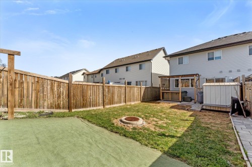 Fenced backyard featuring a wood-sided shed, a raised deck with a pergola, a partial paver walkway, and a circular fire pit - 21818 99A Avenue, Edmonton, AB - Outdoor With Deck Patio Veranda