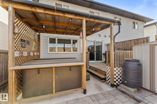 Covered patio area featuring a built-in hot tub, wood trellis, wood deck, sliding glass door, and exterior siding - 21818 99A Avenue, Edmonton, AB - Outdoor With Deck Patio Veranda With Exterior