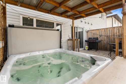 Covered deck featuring a built-in spa, wood deck flooring, privacy fencing, and a sliding glass door - 21818 99A Avenue, Edmonton, AB - Outdoor With Exterior