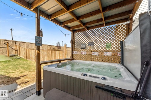 Covered patio featuring an integrated hot tub with a raised lattice privacy screen - 21818 99A Avenue, Edmonton, AB - Outdoor With Deck Patio Veranda With Exterior