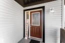 Front entry featuring a brown paneled door with frosted glass, black trim, and a white wall-mounted light fixture - 21818 99A Avenue, Edmonton, AB  - Outdoor With Exterior 