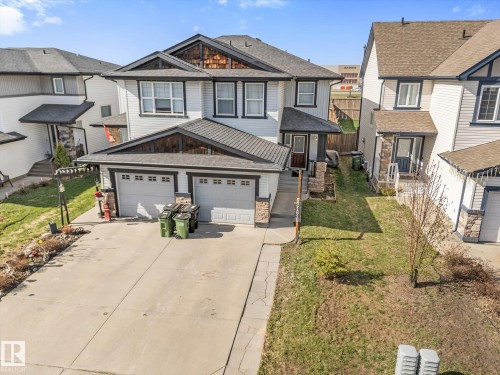 Contemporary two-story residence featuring light-toned horizontal siding, dark trim, and a prominent front-facing double garage with individual doors - 21818 99A Avenue, Edmonton, AB - Outdoor With Facade