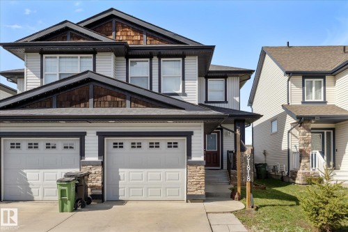 Contemporary multi-level residence featuring light-colored siding, dark trim accents, and a dual garage with carriage-style doors - 21818 99A Avenue, Edmonton, AB - Outdoor With Facade