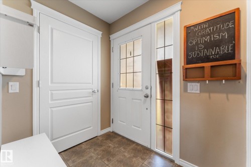 Entryway with brown-toned tile flooring, a white front door featuring glass paneling, and an adjacent white interior door with decorative paneling - 21818 99A Avenue, Edmonton, AB - Indoor Photo Showing Other Room