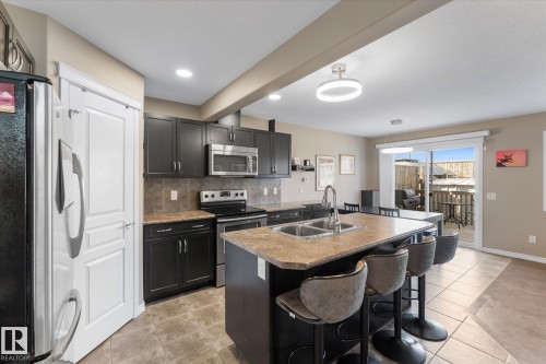 Modern kitchen featuring dark cabinetry, stainless steel appliances, and a central island with an integrated double sink - 21818 99A Avenue, Edmonton, AB - Indoor Photo Showing Kitchen With Double Sink