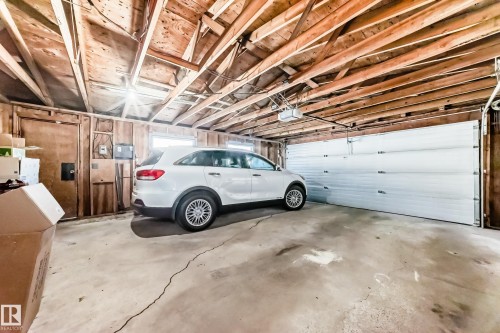 Attached garage featuring exposed wood framing, concrete flooring, and a white paneled garage door with an automatic opener - 3611 108 Street, Edmonton, AB - Indoor Photo Showing Garage