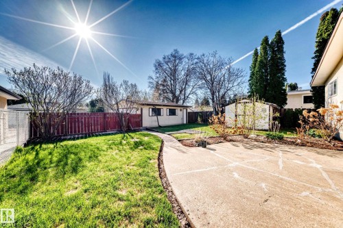 Expansive backyard featuring a curved concrete walkway, a manicured lawn, perimeter fencing, and mature landscaping - 3611 108 Street, Edmonton, AB - Outdoor