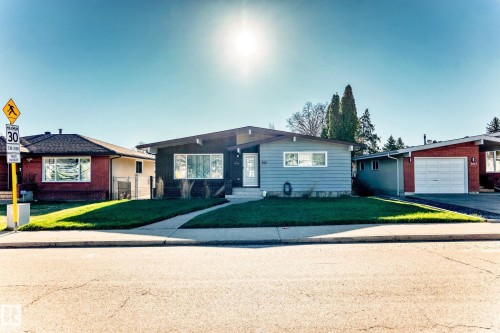 Contemporary single-story residence featuring a distinctive sloped roofline, light blue horizontal siding, and a white entry door - 3611 108 Street, Edmonton, AB - Outdoor
