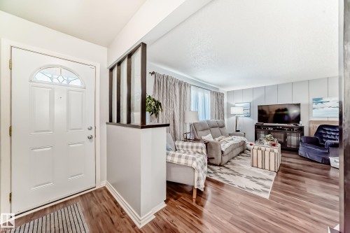 Entryway with a paneled white door featuring an arched decorative glass insert and complementing wood-finish flooring - 3611 108 Street, Edmonton, AB - Indoor