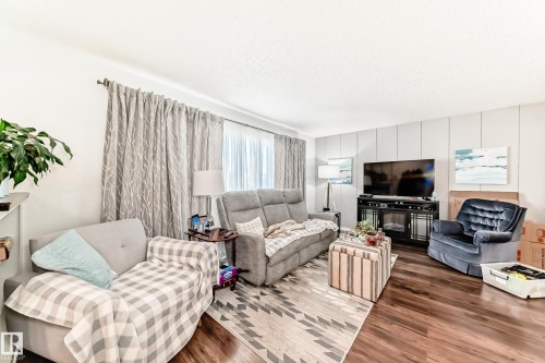 Living area with wood-finish flooring, white walls, and a feature wall with vertical paneling - 3611 108 Street, Edmonton, AB - Indoor Photo Showing Living Room