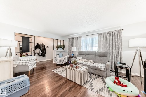 Spacious living area featuring rich wood-finish flooring and ample natural light from a large window - 3611 108 Street, Edmonton, AB - Indoor Photo Showing Living Room