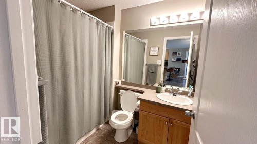 The bathroom features a vanity with wooden cabinetry, a countertop, and an oval sink - 1112 9363 Simpson Drive, Edmonton, AB - Indoor Photo Showing Bathroom