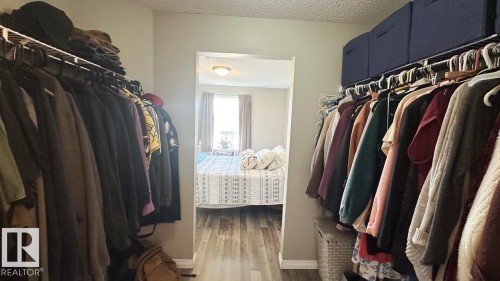 Walk-through closet featuring hanging storage and overhead shelving, with wood-style flooring visible - 1112 9363 Simpson Drive, Edmonton, AB - Indoor With Storage
