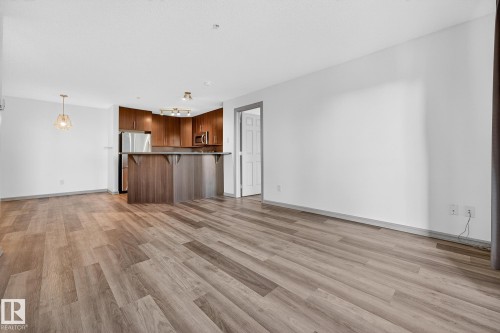 Open-concept living space featuring wood-finish flooring, a kitchen island with seating, stainless steel appliances, and recessed lighting - 215 2208 44 Avenue, Edmonton, AB - Indoor Photo Showing Kitchen