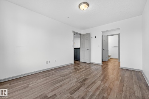 Spacious room featuring wood-finish flooring, white walls, and a semi-flush mount ceiling light - 215 2208 44 Avenue, Edmonton, AB - Indoor Photo Showing Other Room