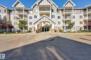 Multi-story residential building featuring a prominent central entrance with an arched portico, framed by gabled rooflines - 215 2208 44 Avenue, Edmonton, AB  - Outdoor With Balcony With Facade 