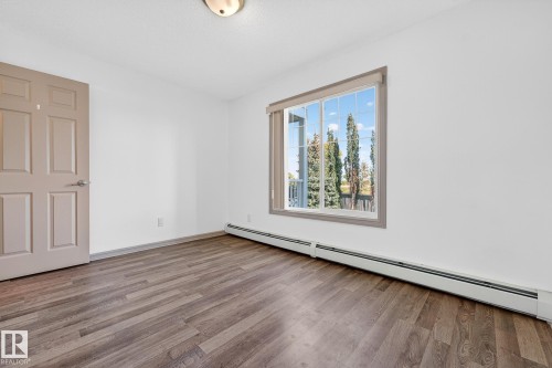 Room featuring neutral wall tones, wood-finish flooring, and a large window - 215 2208 44 Avenue, Edmonton, AB - Indoor Photo Showing Other Room