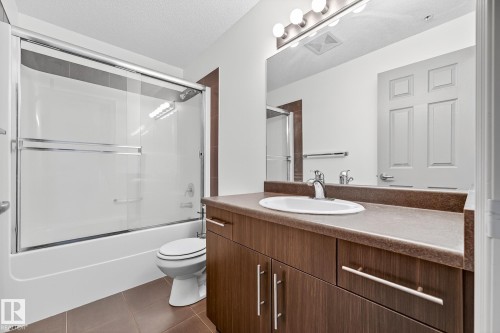 Bathroom featuring a wood-finish vanity with a single basin sink and chrome faucet - 215 2208 44 Avenue, Edmonton, AB - Indoor Photo Showing Bathroom