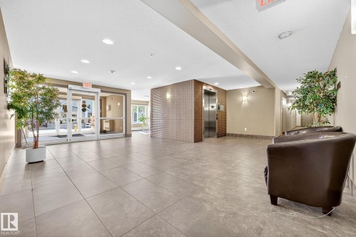 Spacious lobby featuring large format floor tiles, automatic sliding glass doors, a stainless steel elevator, and recessed lighting - 215 2208 44 Avenue, Edmonton, AB - Indoor Photo Showing Other Room