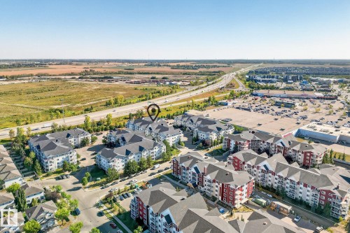 Aerial perspective showcasing multi-building residential complexes with varied architectural styles, including light-colored and red-toned facades - 215 2208 44 Avenue, Edmonton, AB - Outdoor With View