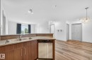 Kitchen featuring wood-finish cabinetry, a stainless steel double sink, and a built-in dishwasher - 215 2208 44 Avenue, Edmonton, AB  - Indoor Photo Showing Kitchen With Double Sink 