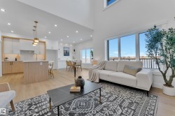 Open-concept living space featuring high ceilings, light wood-finish flooring, and large windows - 