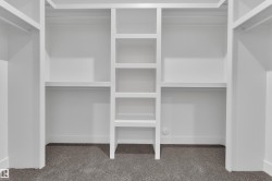 Built-in white storage system featuring multiple shelves and hanging rods - 