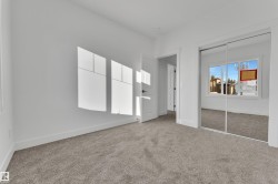 Room featuring neutral carpeting, white walls, white baseboards, a white interior door with dark hardware, and a mirrored closet with sliding doors - 