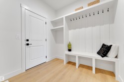 Built-in white storage bench with integrated coat hooks and upper shelving - 