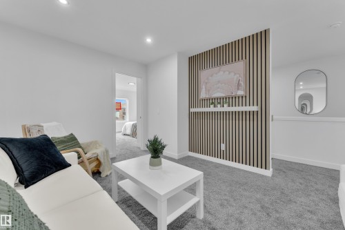 Recessed lighting illuminating a carpeted living space with a distinct slatted accent wall and a built-in display shelf - 259 Linden Loop, Leduc, AB - Indoor Photo Showing Other Room