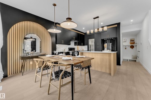 Open-concept living area featuring a modern kitchen with black cabinetry, a light wood-finish island with a white countertop, and light wood-finish flooring - 259 Linden Loop, Leduc, AB - Indoor Photo Showing Dining Room