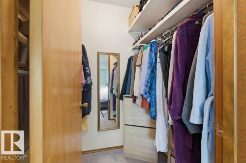 Walk-in closet featuring extensive shelving, hanging rods, light wood-finish built-in drawers, and wall-mounted mirror - 8608 22 Ave, Edmonton, AB - Indoor With Storage